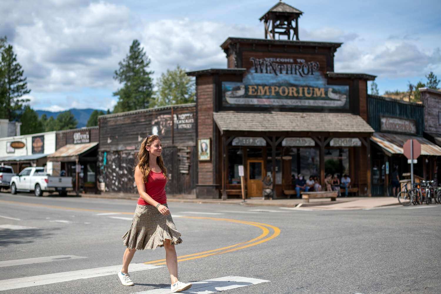 A woman walks across the street in front of an Old-West style building in Winthrop.