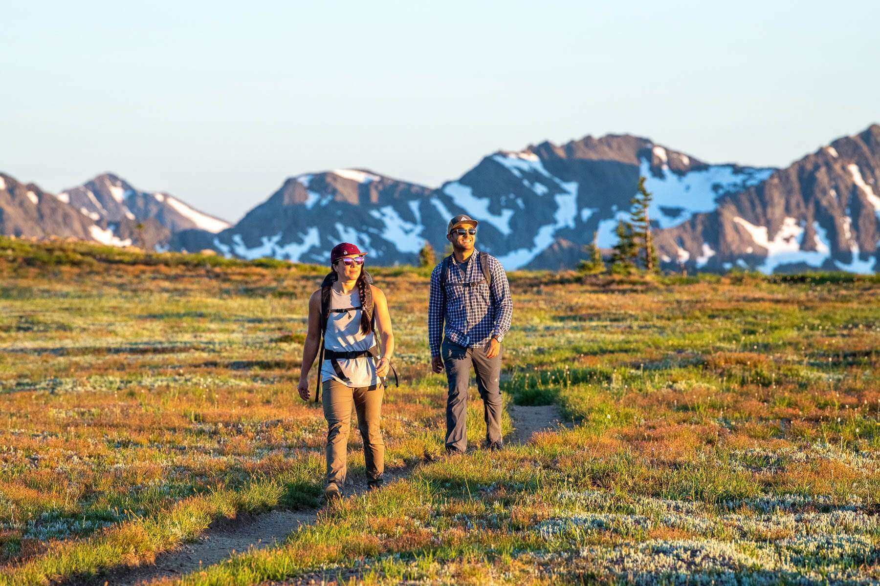 Man and woman walking along a trail in fall with a mountain in the background