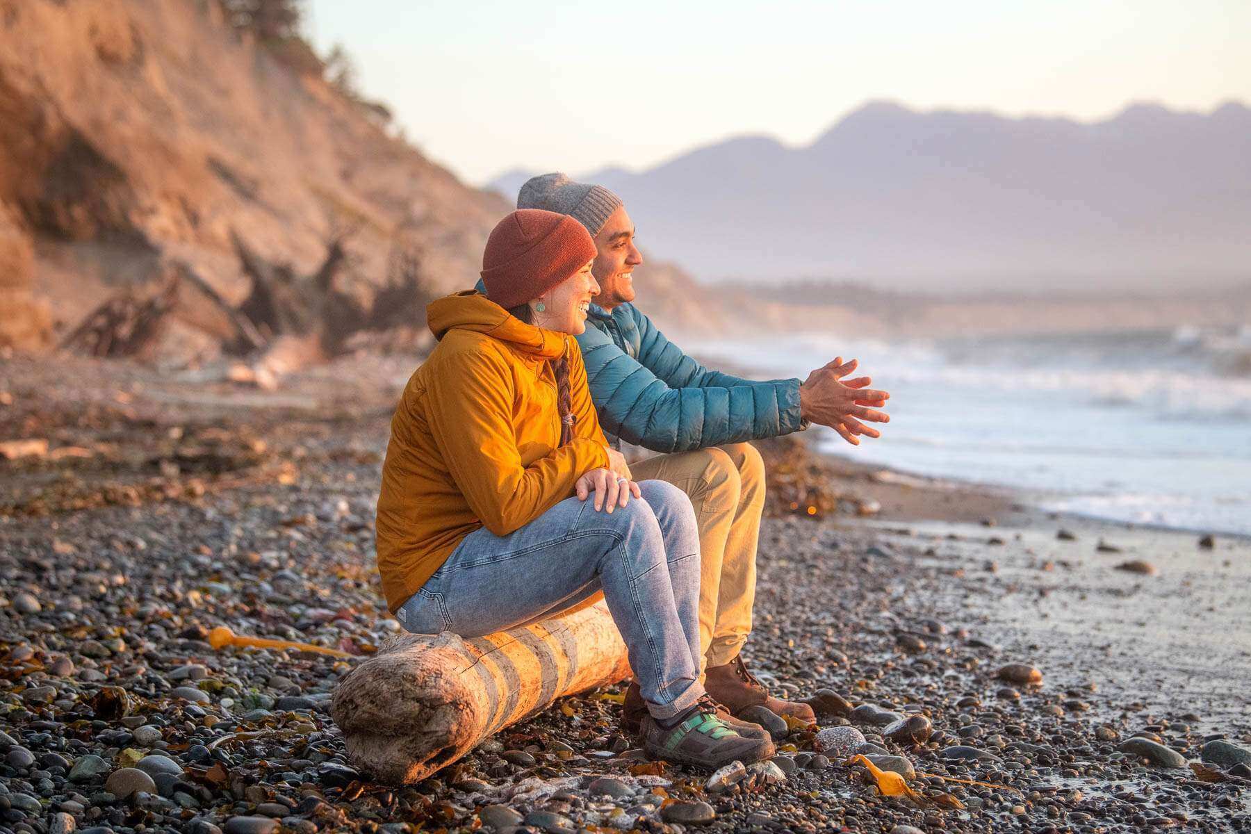 Couple sitting on a log along the beach in the Peninsulas Region of Washington