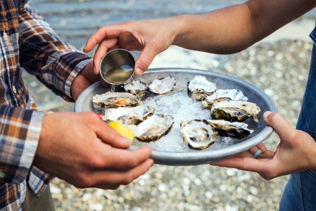 Oysters on a plate held by two people