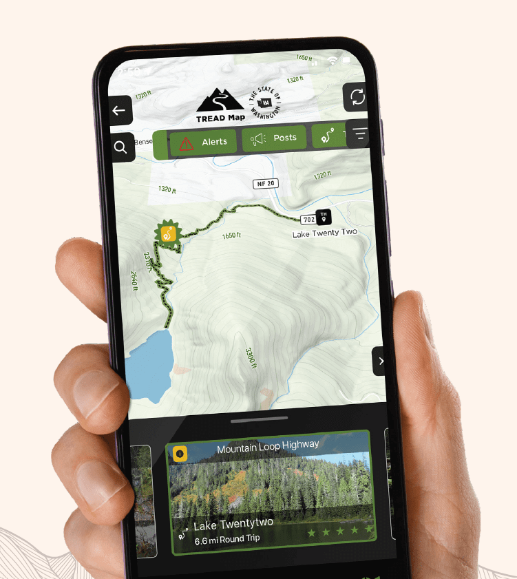 Hand holding a smartphone showing a trail in the TREAD Map App