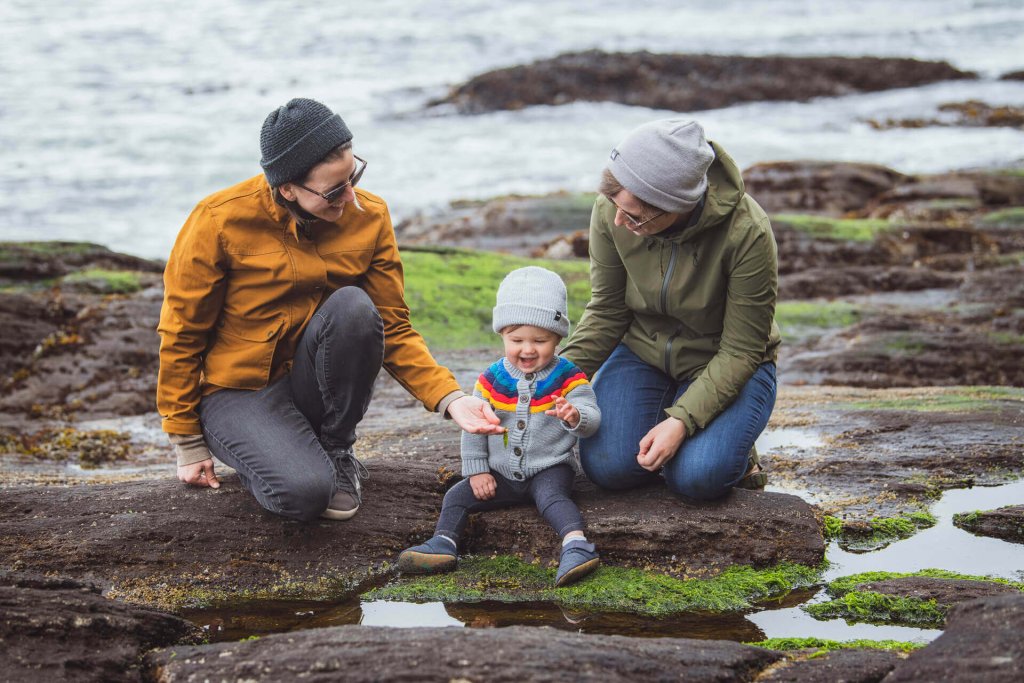 Two women show a small child a tidepool along the coast of Washington.