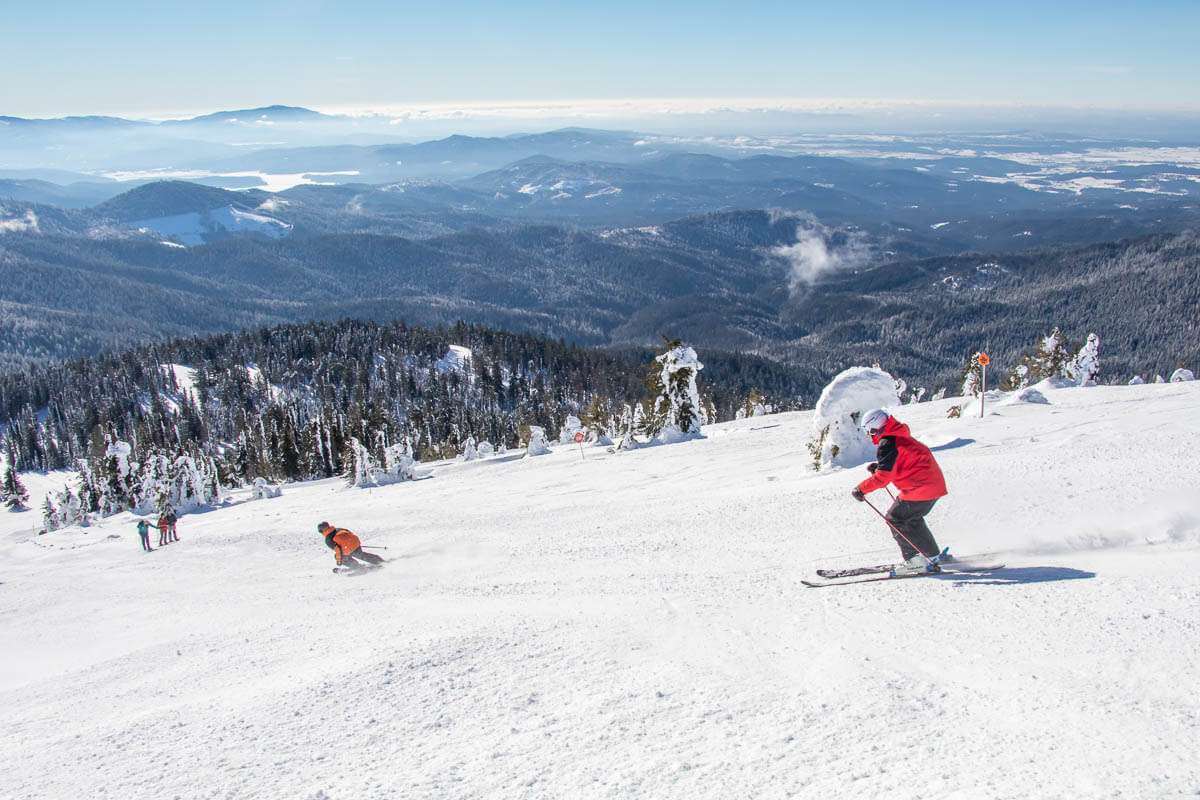 A person in a red jacket downhill skiing at Mt. Spokane