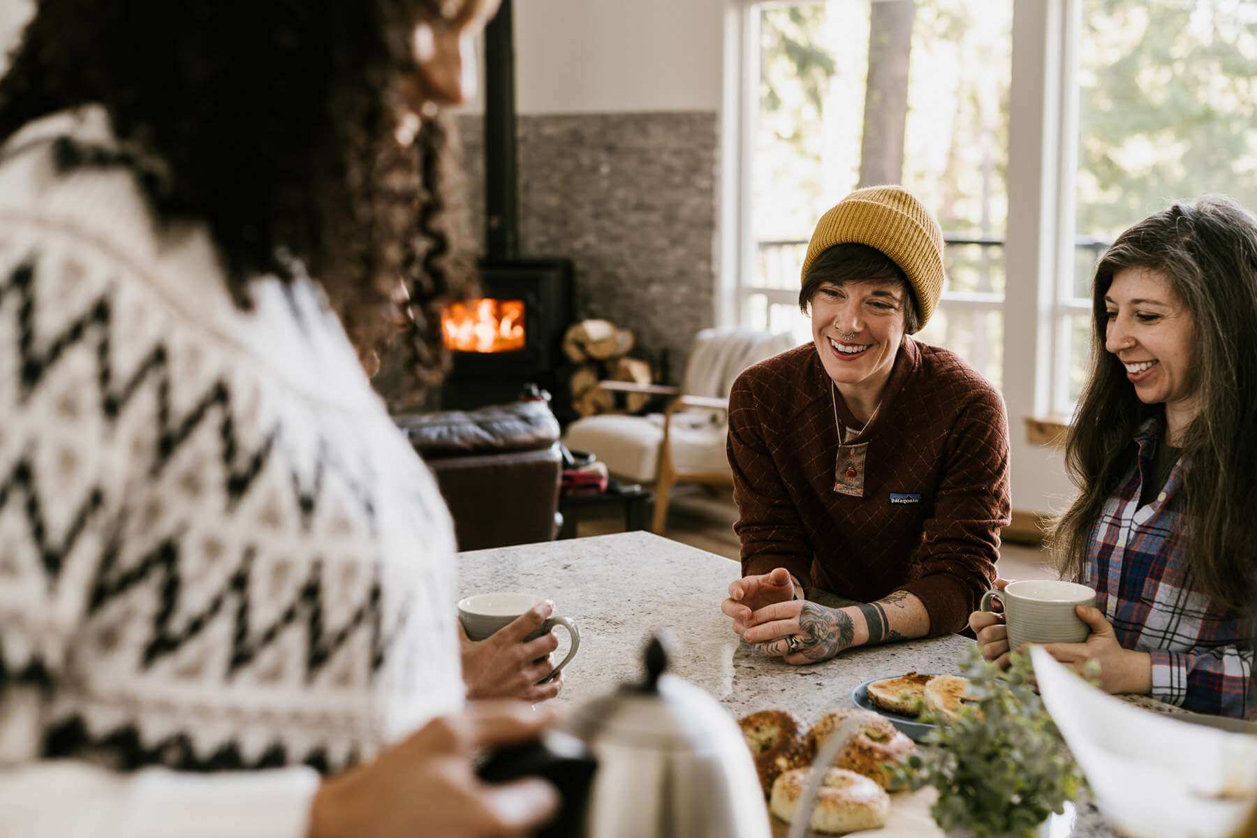 Three women drinking coffee in a cabin during a winter getaway in the Cascade Mountains