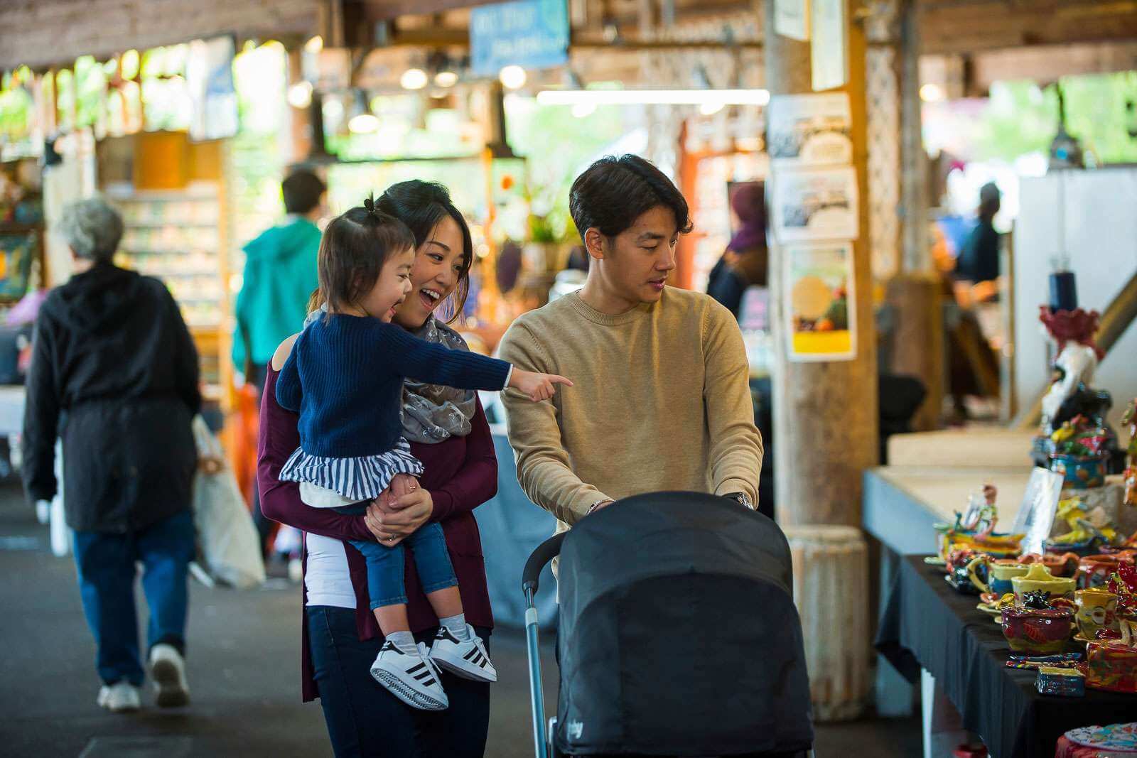 A couple, with the woman holding a little girl, look at pottery at a market in Olympia