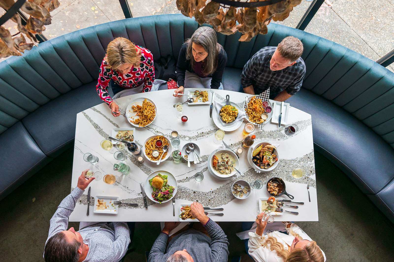 View of six adults eating burgers and other food inside a restaurant