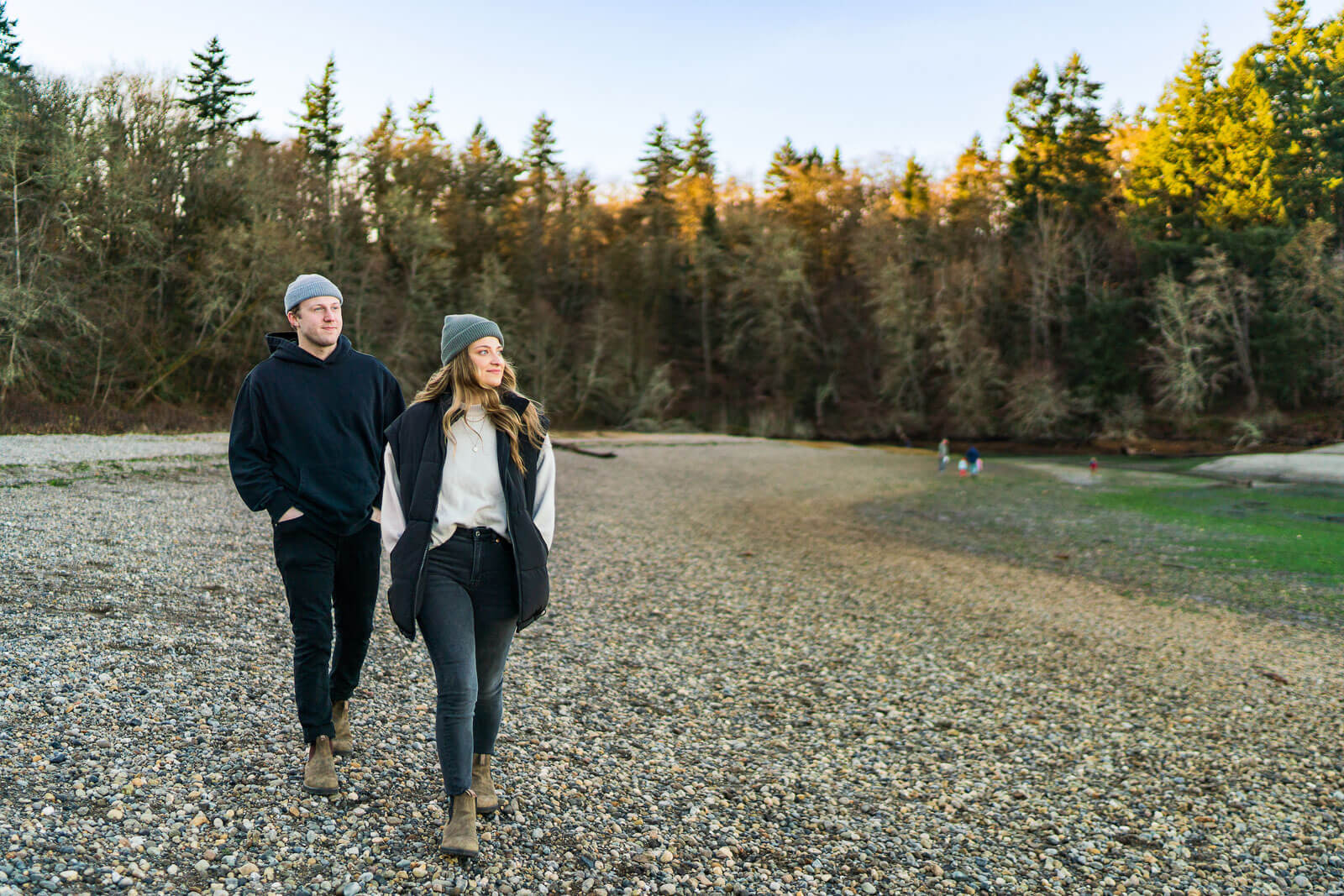 Man and woman walk along a pebble beach at low tide