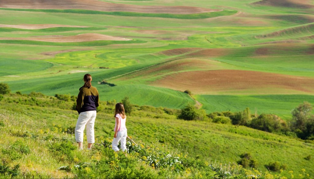A woman and child stand on a hill overlooking the Palouse region