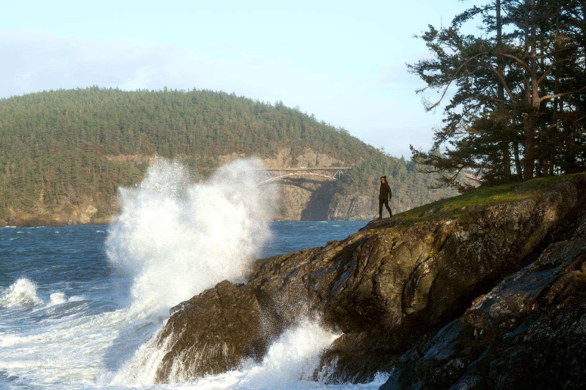 A man watches waves crash along the shore at Deception Pass State Park on Whidbey Island