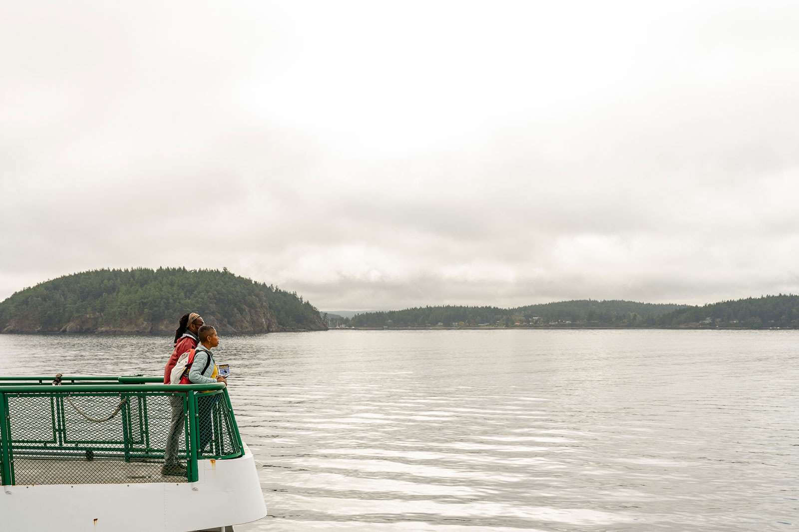 A mother and son stand on the deck of a ferry heading to the San Juan Islands, a stop on the Salish Sea oyster road trip 