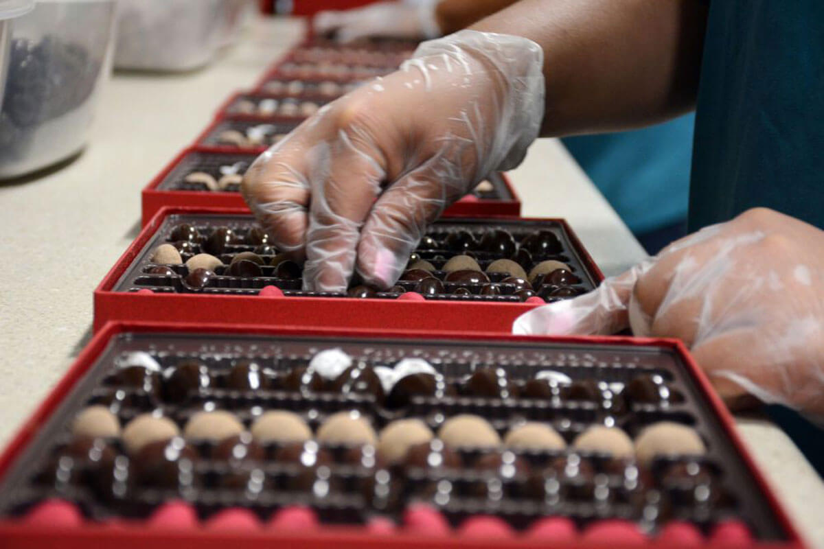 Chukar Cherries, a locally made Washington chocolate, is packed into a box by a worker wearing gloves.