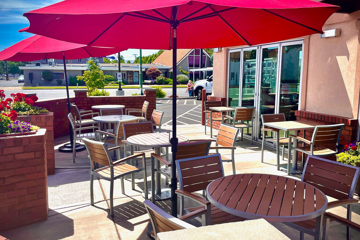 Outdoor patio seating with red umbrellas at Caffe 11th Avenue. 