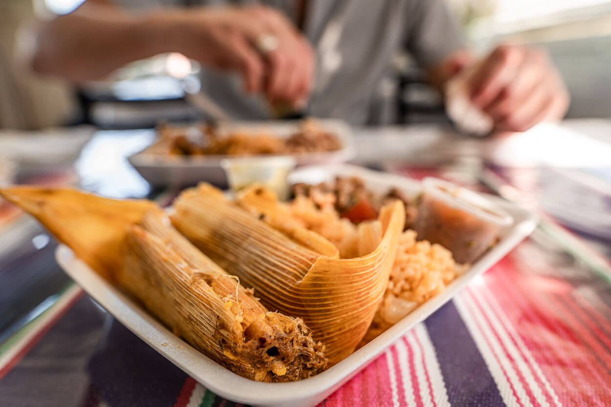 A plate of fresh tamales, rice, and beans.