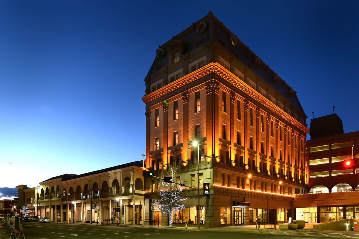 A hotel exterior is illuminated at night in downtown.