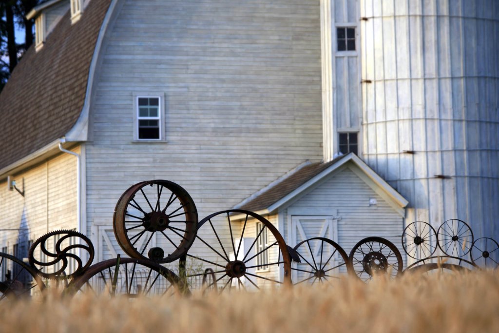 A white barn with a fence made of old rusted wheels from farm equipment is a popular stop on the Palouse Scenic Byway. 