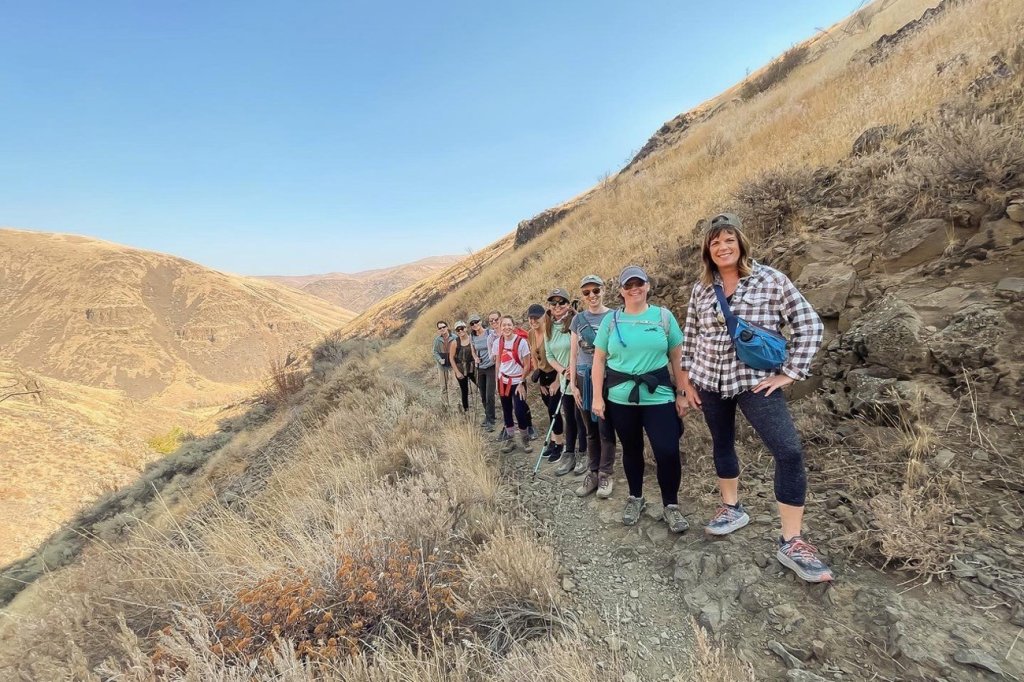 A group of women stand on a hiking trail.