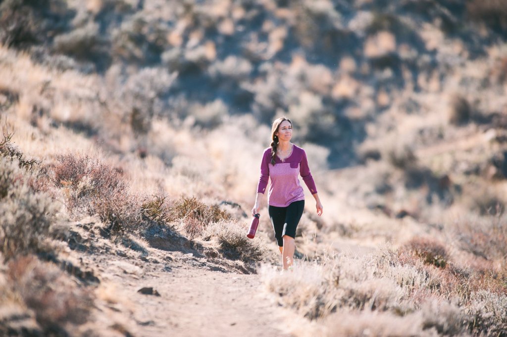 A woman in athletic wear hikes along a trail.