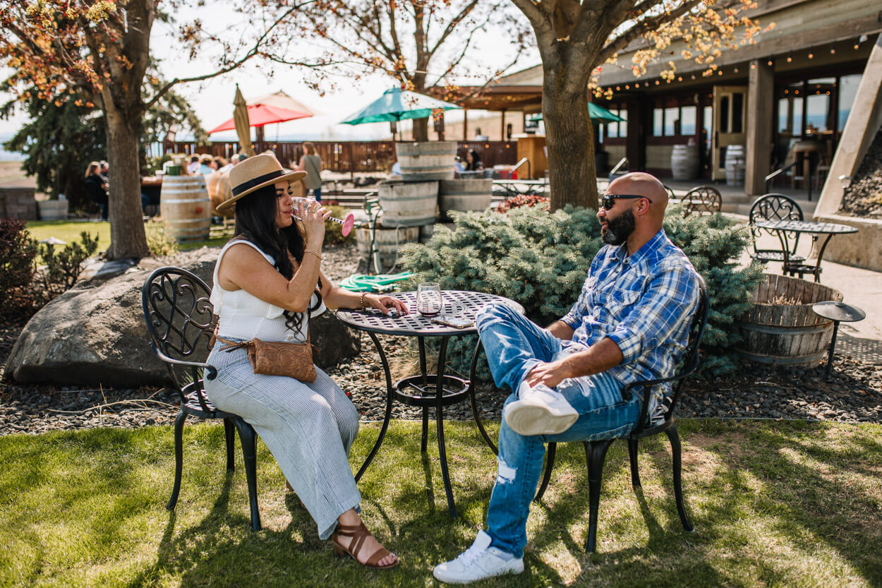 A man and woman sit at a table and drink wine outside during the Spring Barrel event in the Yakima Valley.
