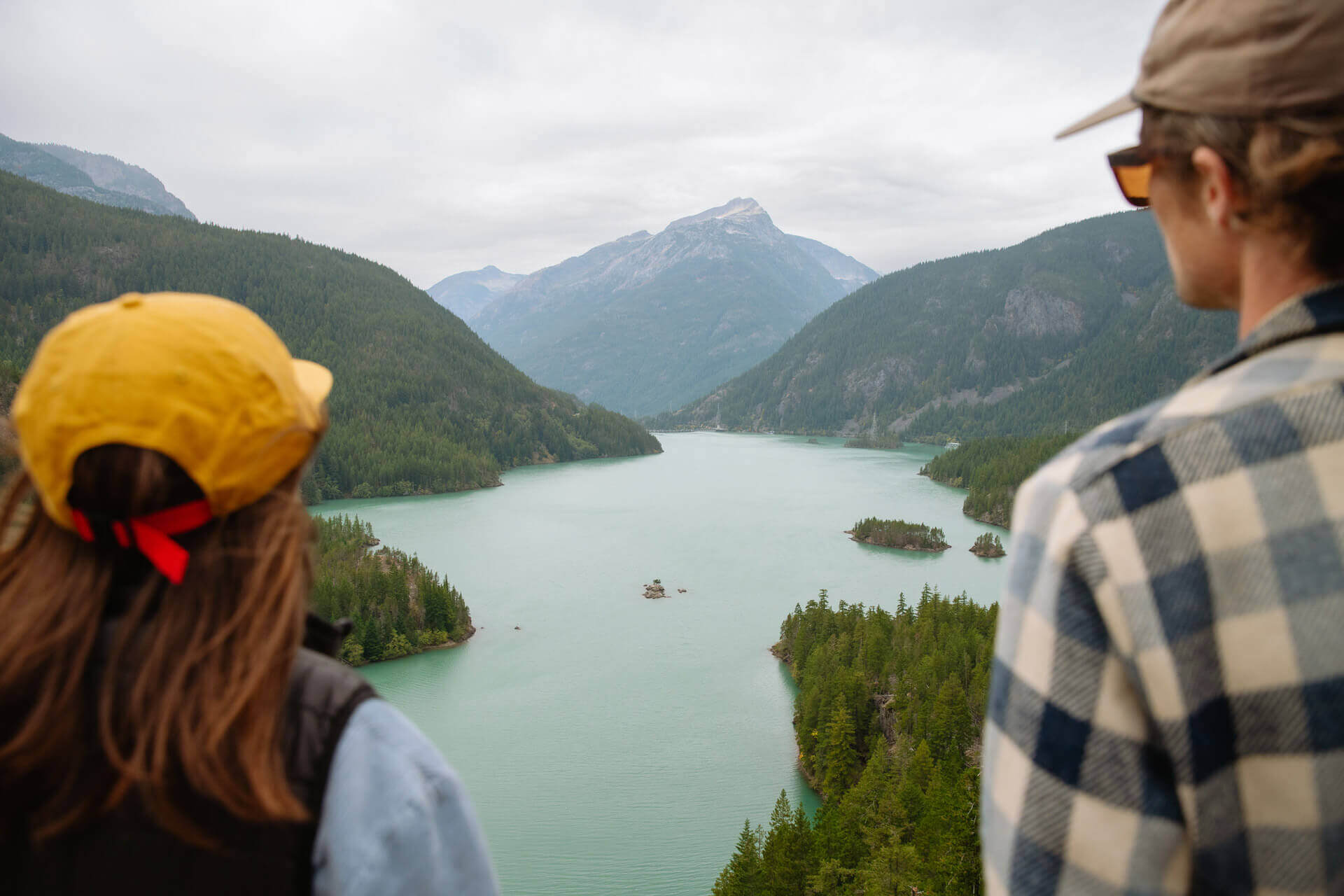 A man and woman stand at viewpoint overlooking Diablo Lake in North Cascades National Park.