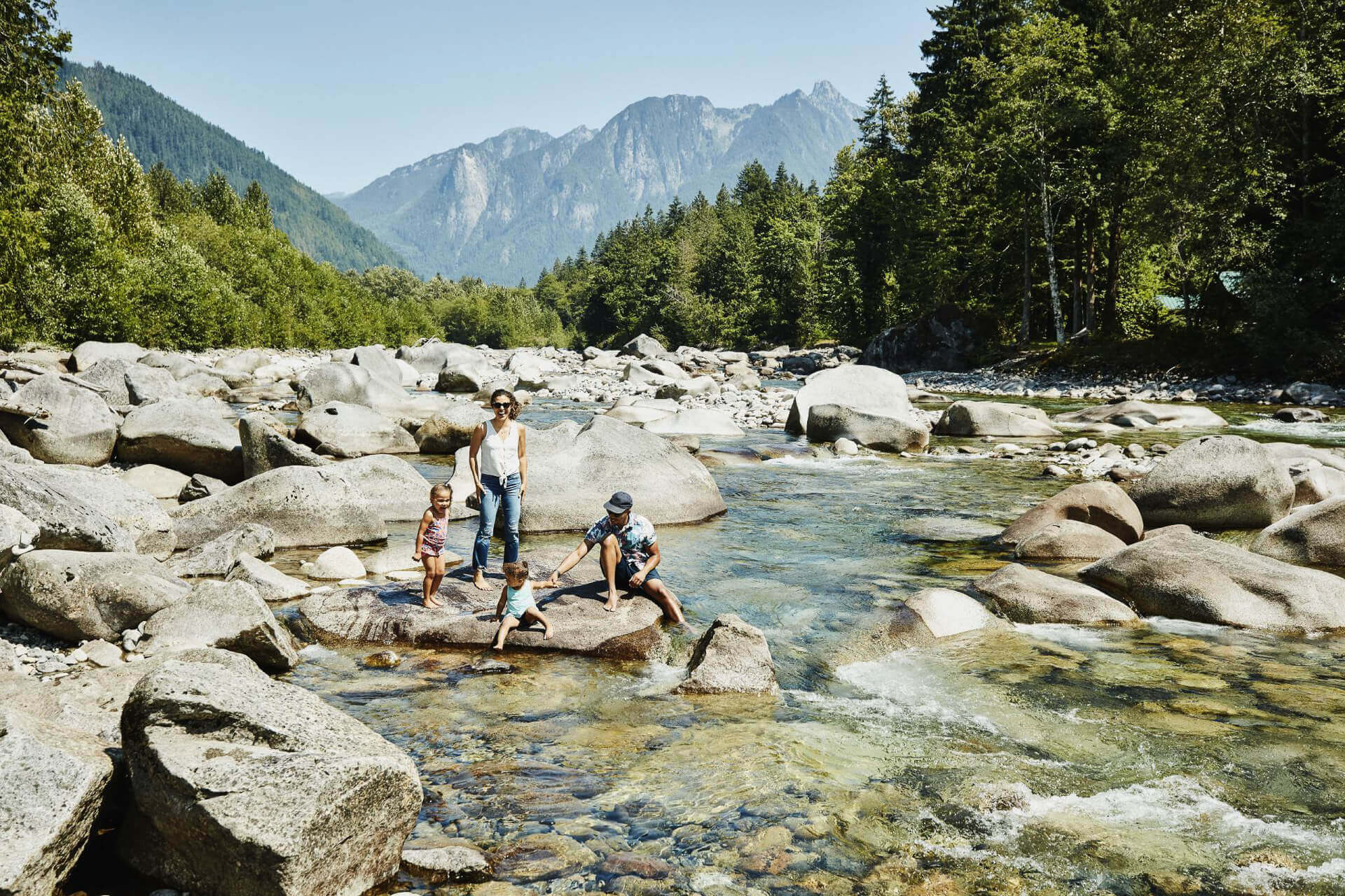 A family sits on a rock along a river in North Cascades National Park.