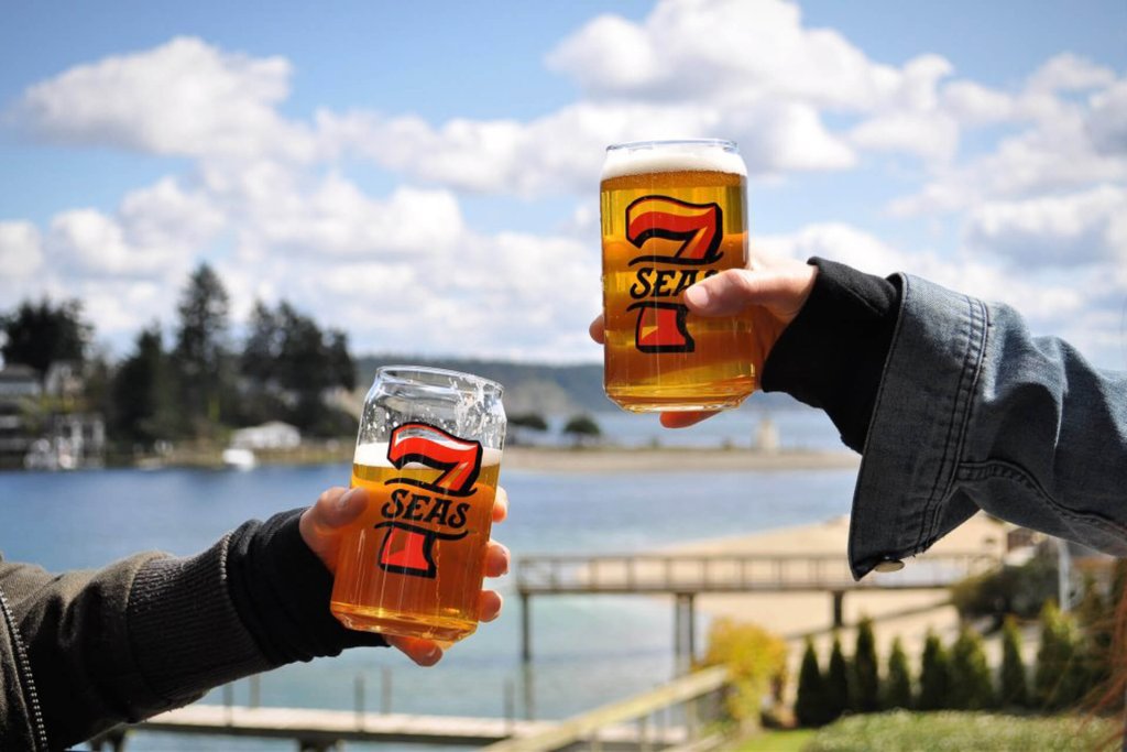 Hands hold pints of beer at 7 Seas Brewing