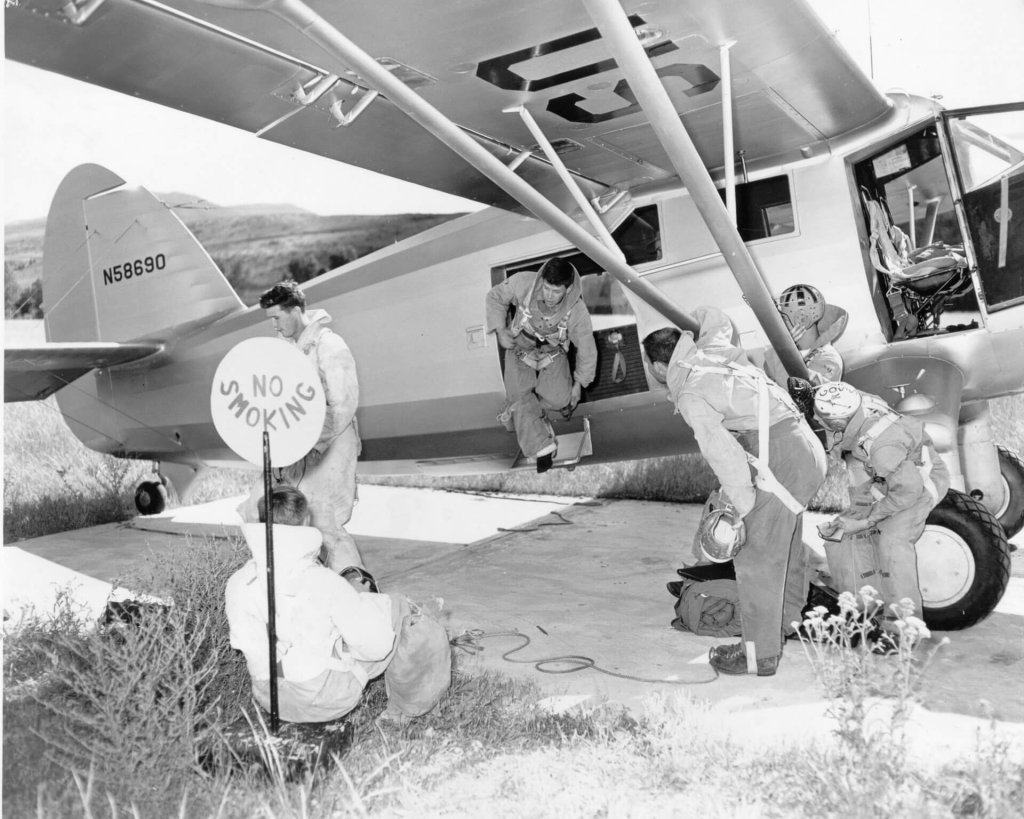 An old black-and-white photo showing smokejumpers standing outside a plane.