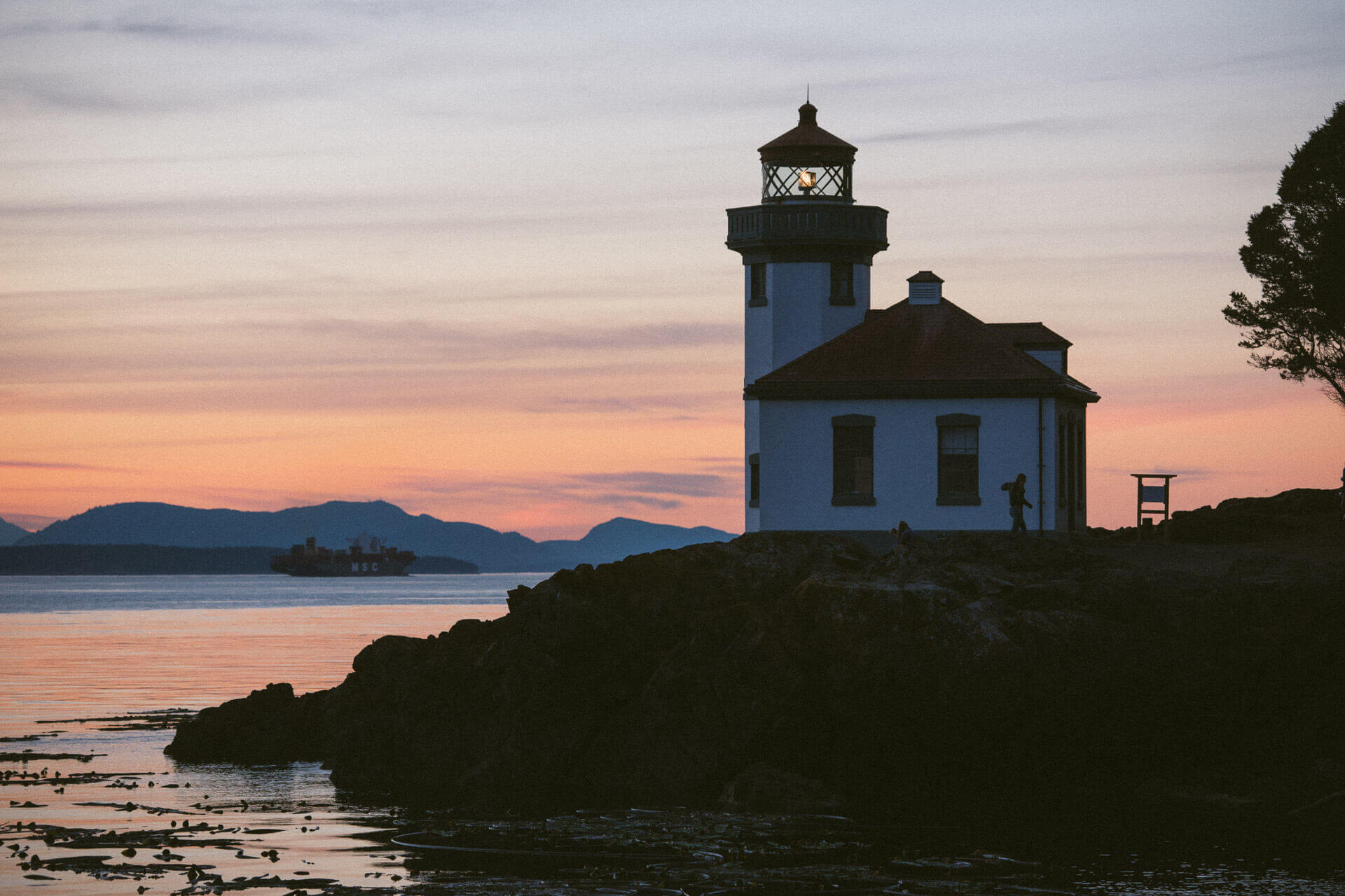Lime Kiln Lighthouse is silhouetted against a sunset.