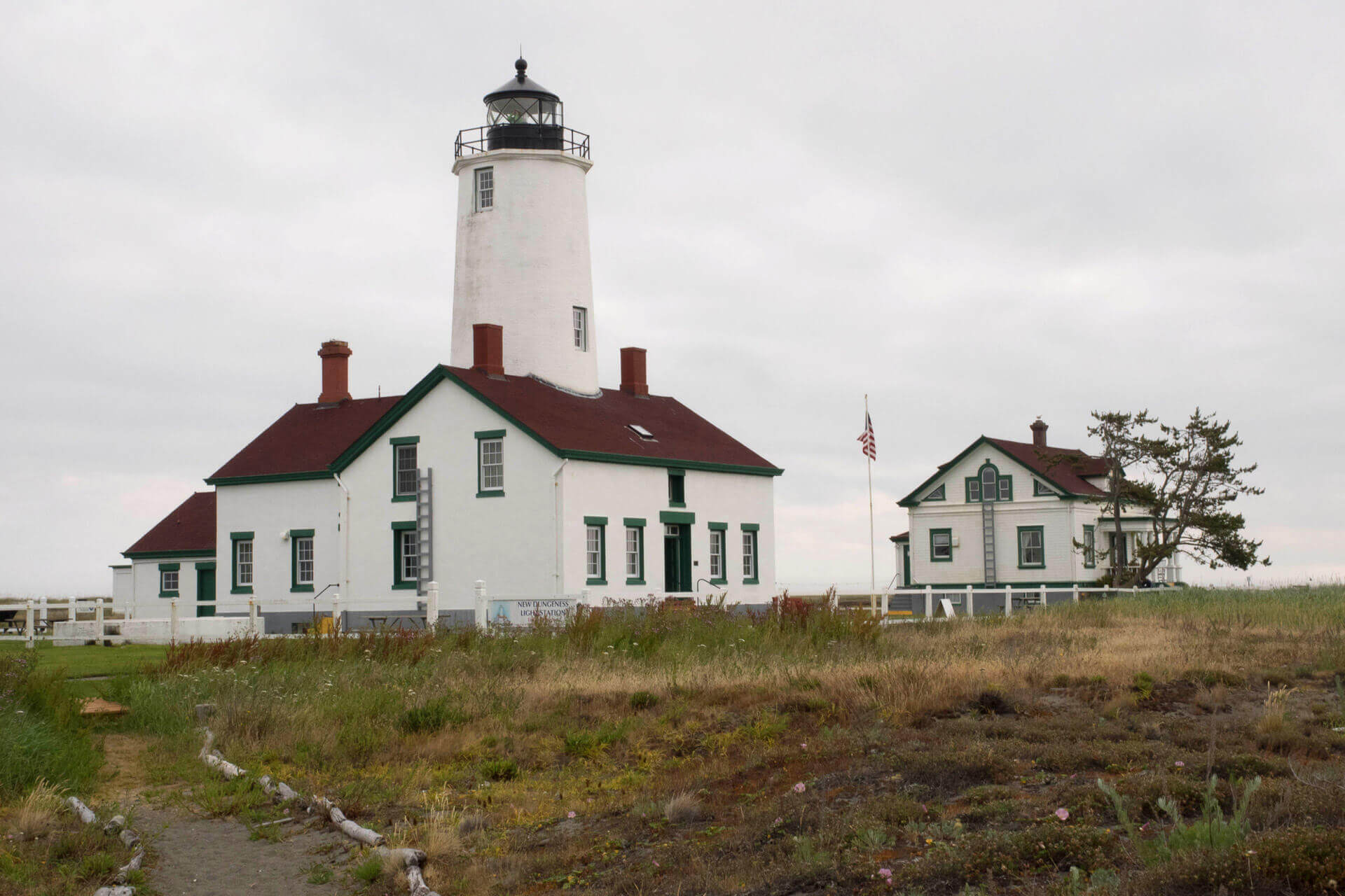 New Dungeness Lighthouse in Washington and adjacent buildings. White exterior with green trim and red roofing.
