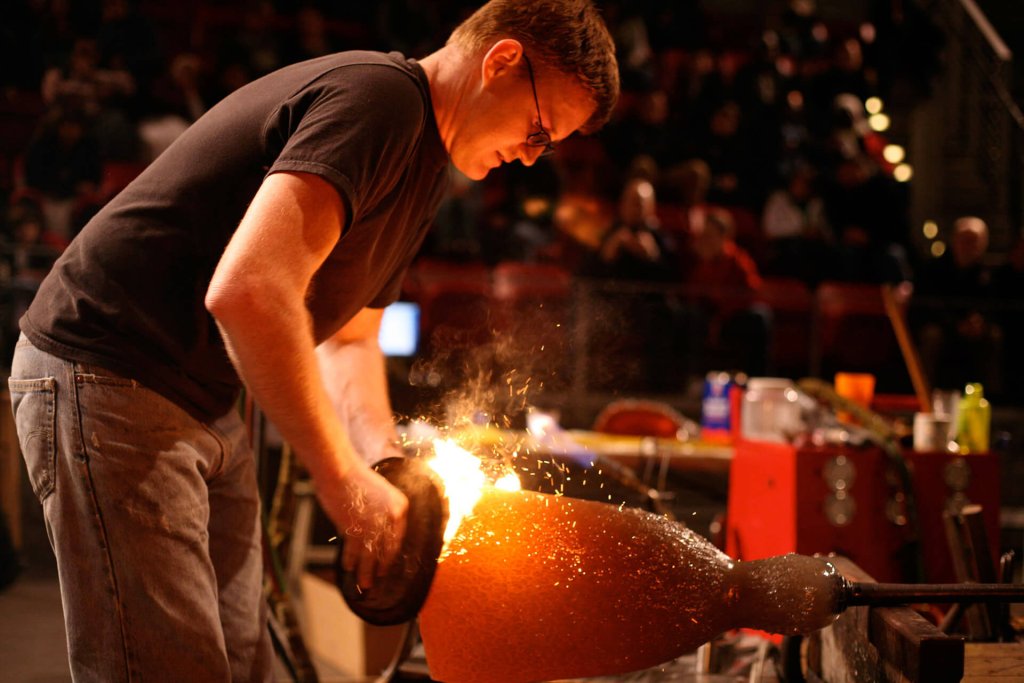 A glass artist works molten glass in the hot shop at the Museum of Glass in the Metro Puget Sound region