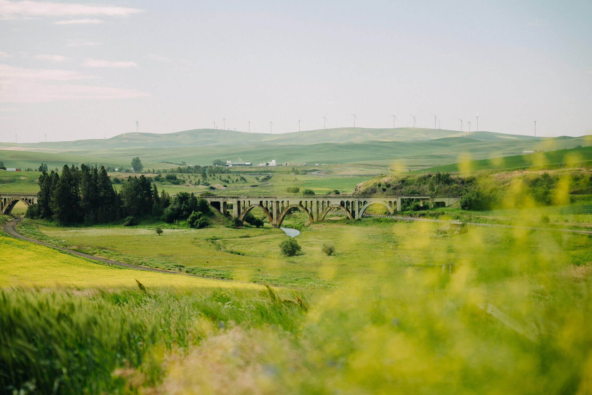 A stone bridge is seen in the distance surrounded by rolling green hills. 