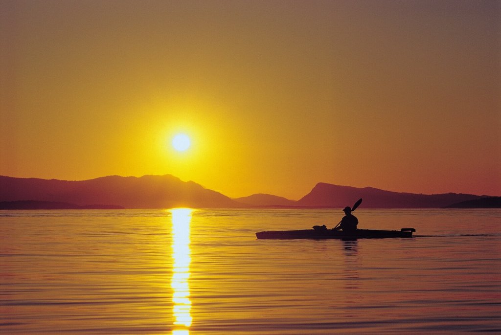 A kayaker is silhouetted at sunset in the San Juan Islands. 