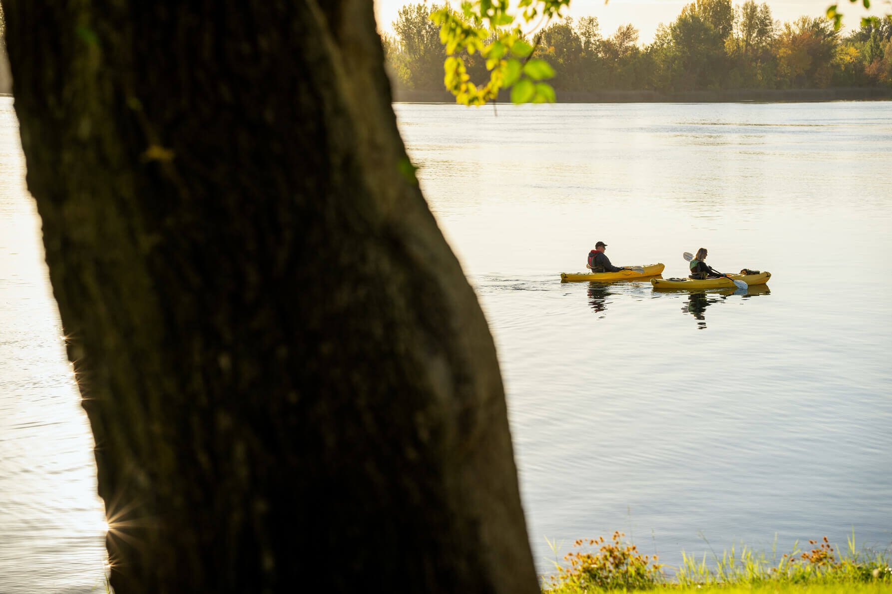 Two people enjoy kayaking along a river in Washington. 