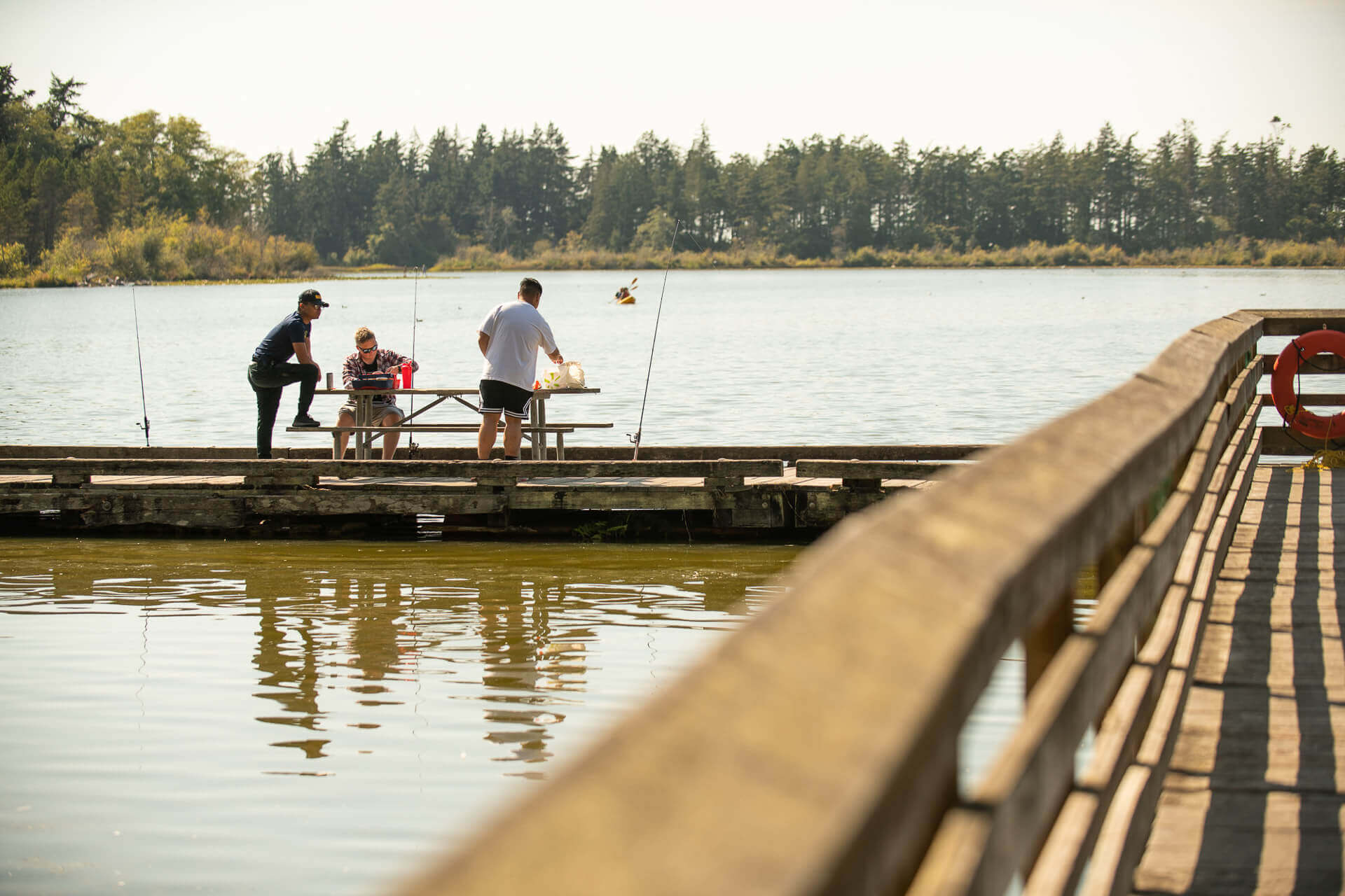 Three people fish from a peir over the water at Deception Pass State Park