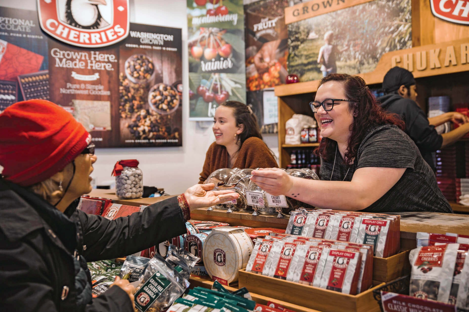 A woman beind a counter hands a customer a sample in the Chukar Cherries store