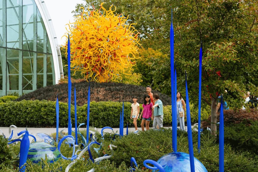 A family walks through the garden at Chihuly Garden and Glass in Seattle, WA.