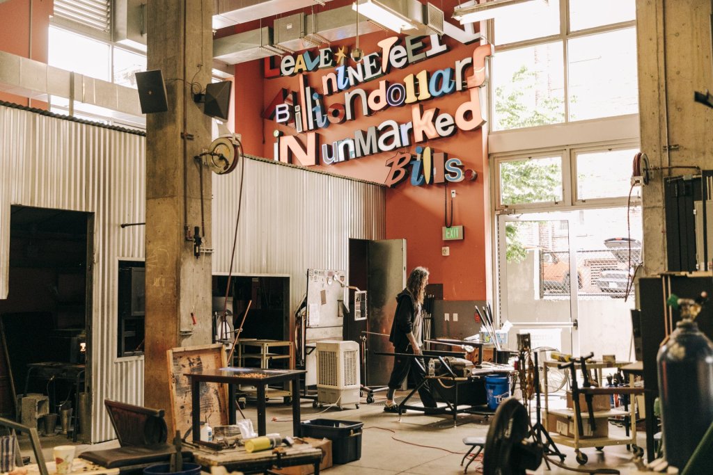 An artist works on glass in a large workshop space