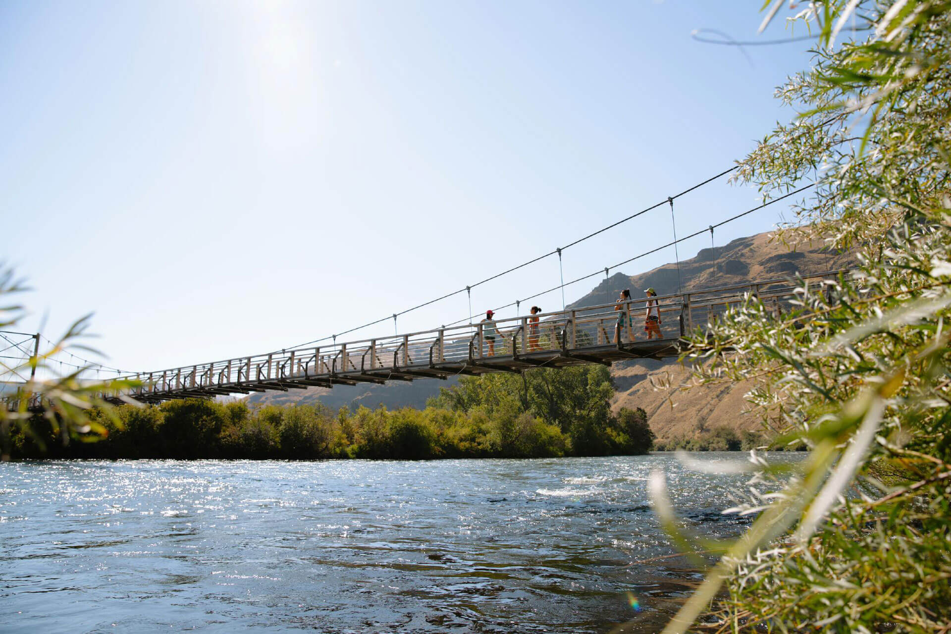 A group of people walk across a bridge over the Yakima River