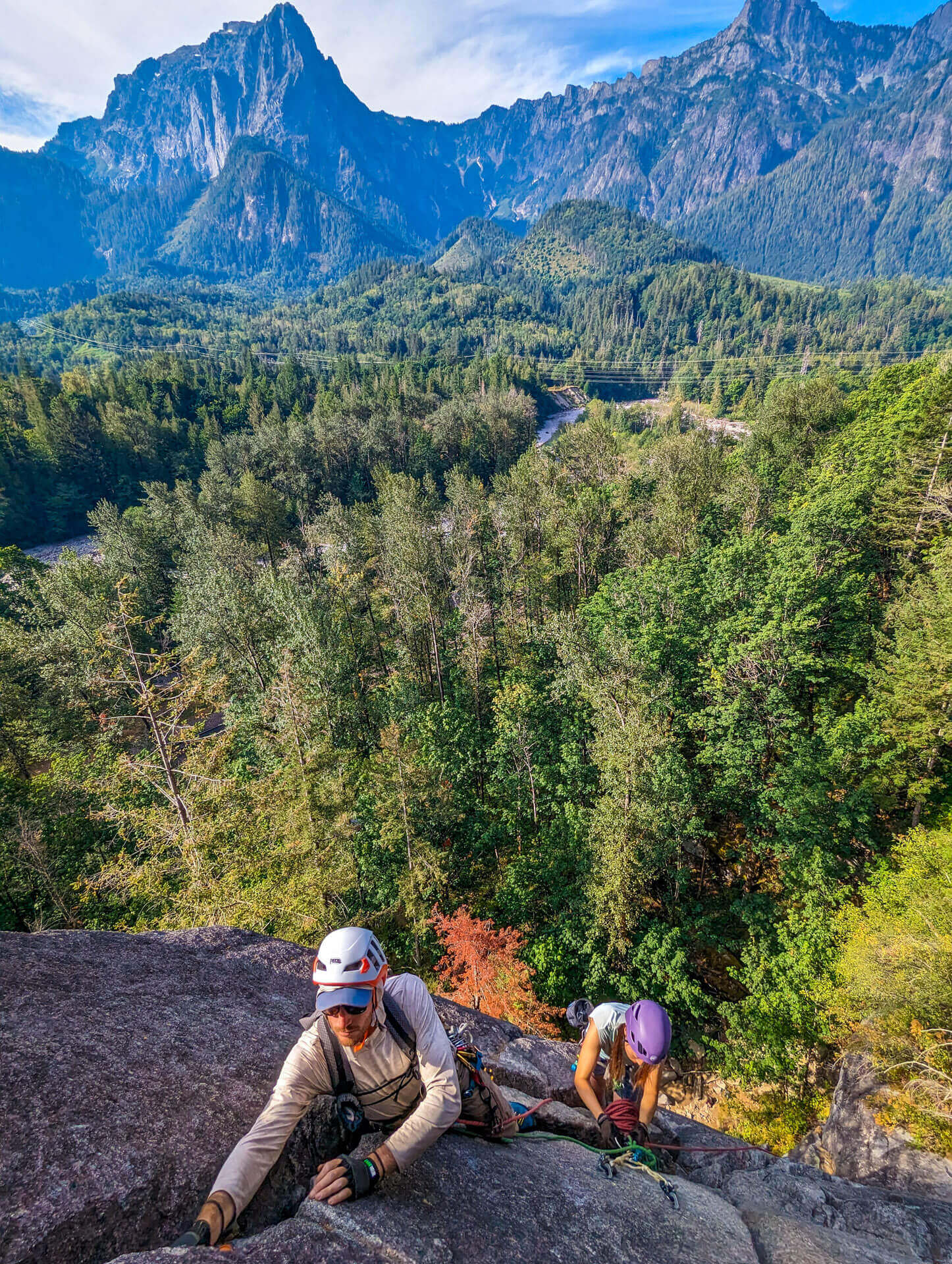 A man and a woman in helmets and gear go rock climbing in Washington near Index. 