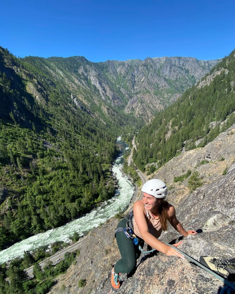 A woman in a helmet and harness enjoys rock climbing in Washington.