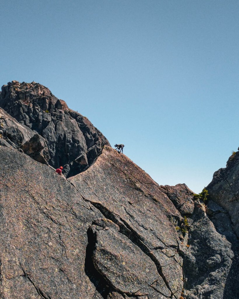 Two people are seen ckimbing a rock face.