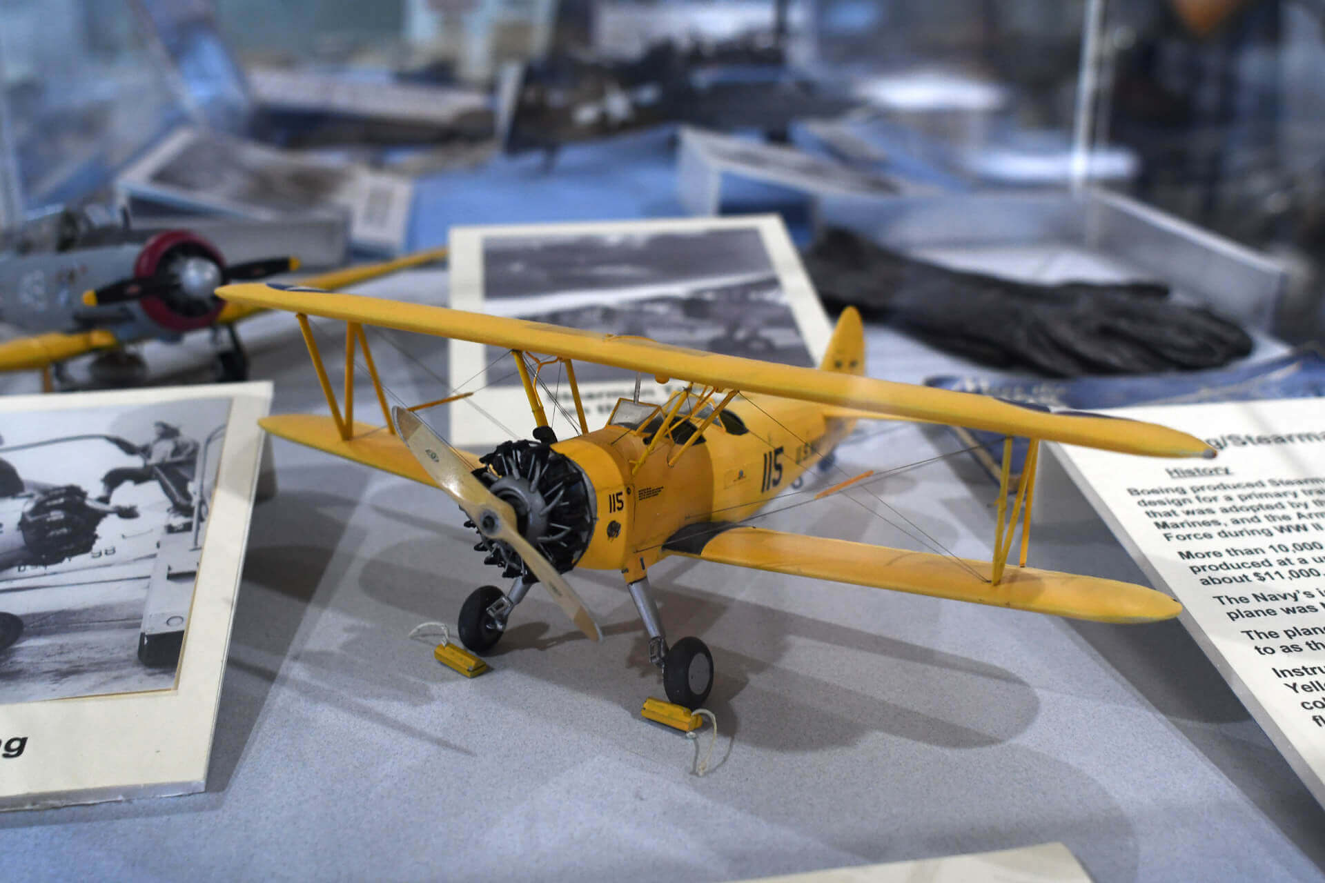 A small yellow model plane on display at an aviation museum