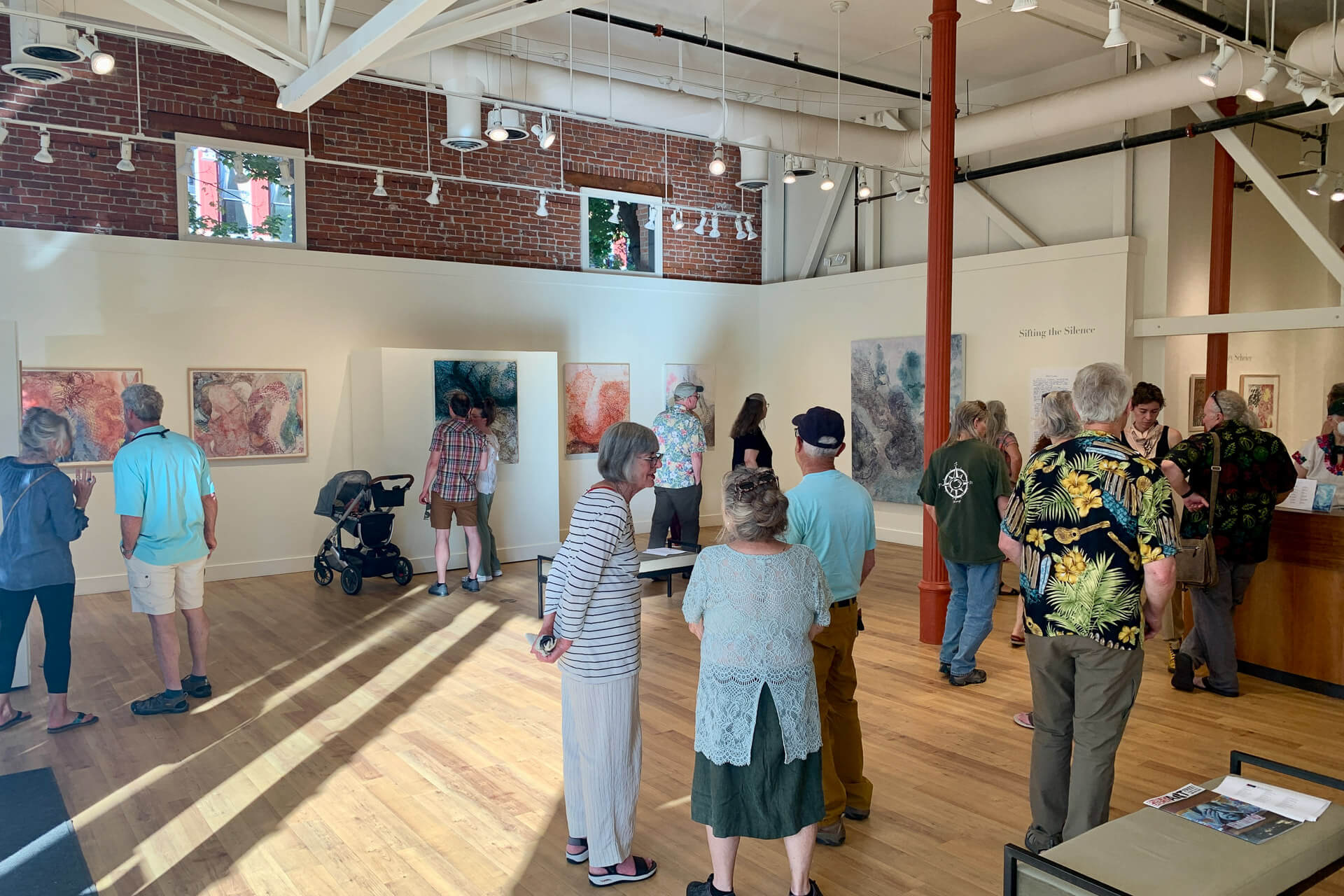 Attendees look at art in a gallery.