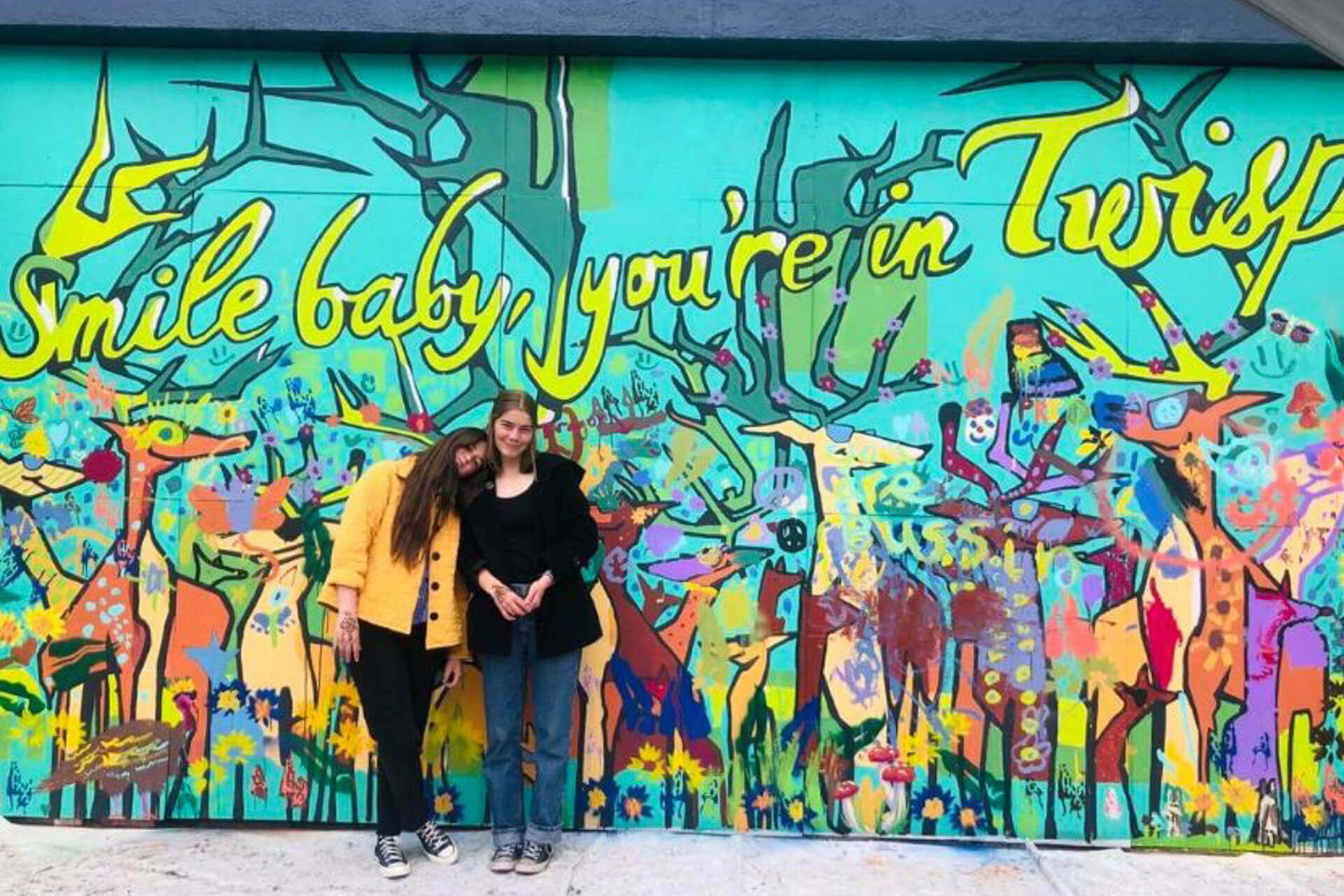 Two women stand in front of a mural in the Twisp Creative District in Washington State