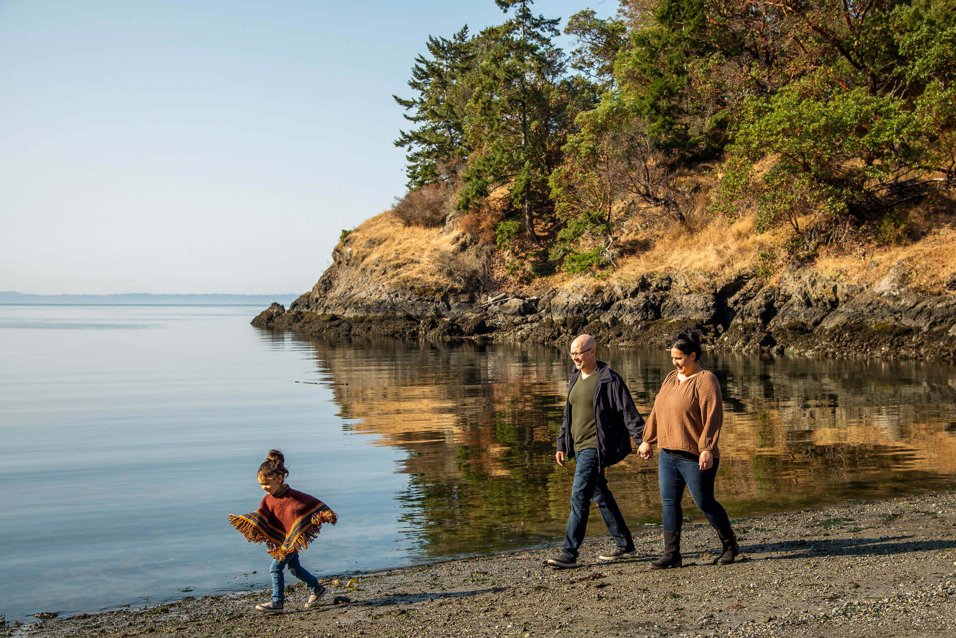 Photo of a man, woman, and child walking along a beach in fall on San Juan Island.