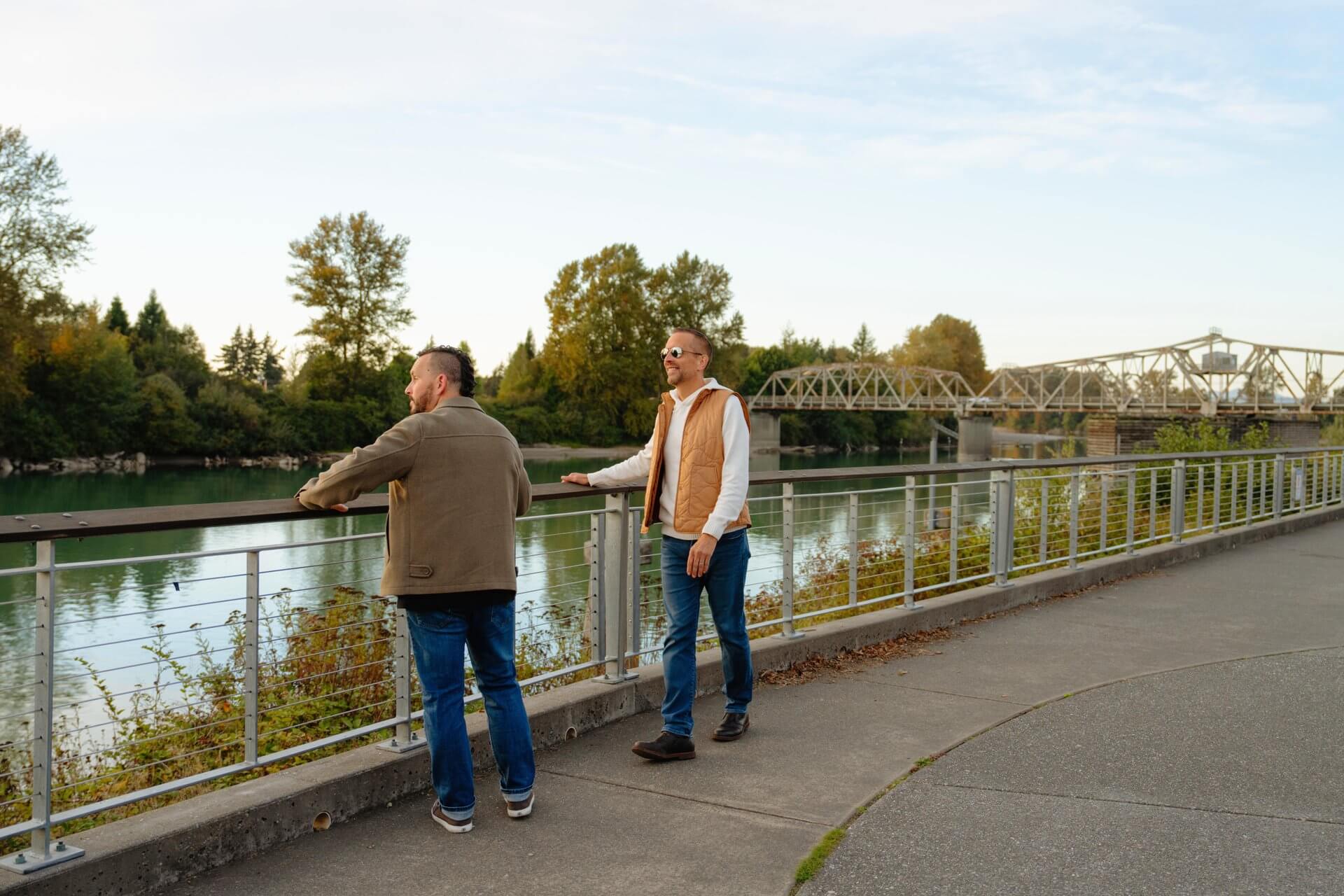 Two men stand on a walking path and look out at the Skagit River.