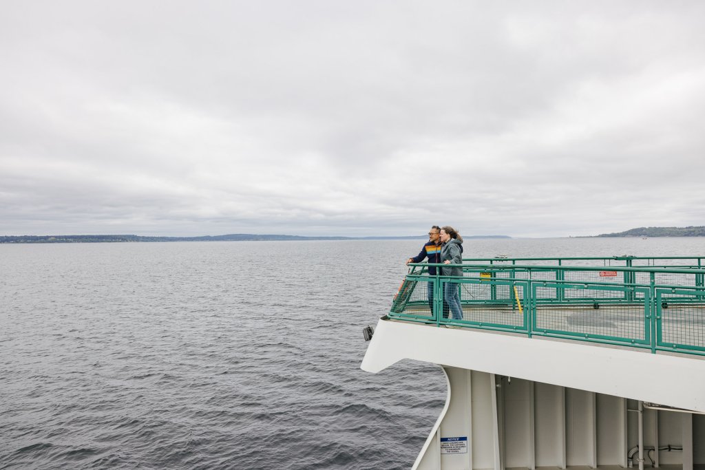 A couple stands on the deck of a ferry boat traveling to Bainbridge Island.