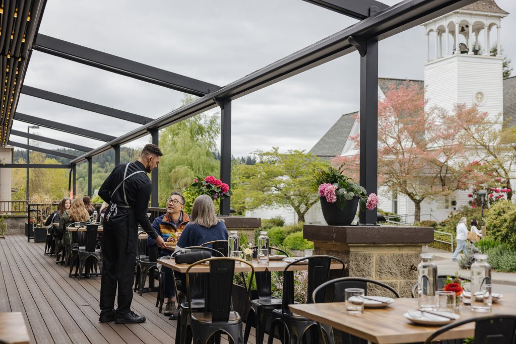 A waiter serves a couple at an outside table at Ba Sa Restaurant
