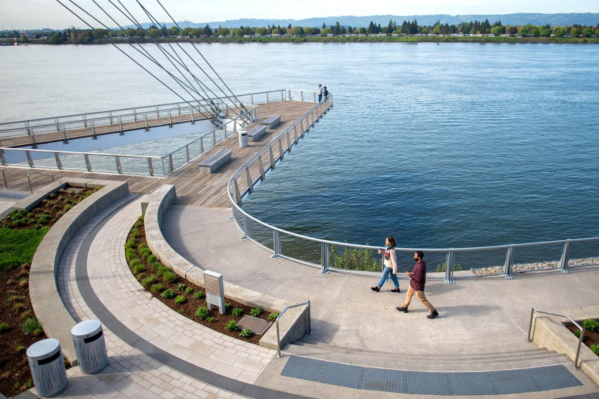 A man and woman walk along the Vancouver waterfront near an overlook