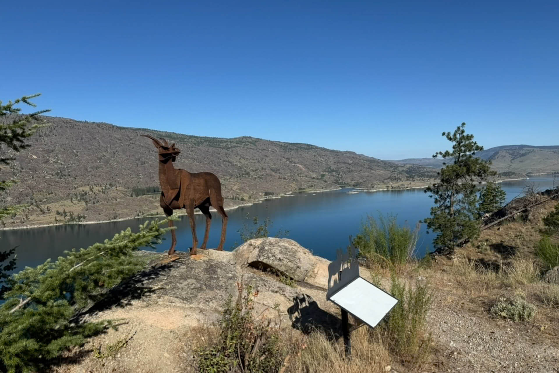 A metal sculpture on a rock overlooking a river