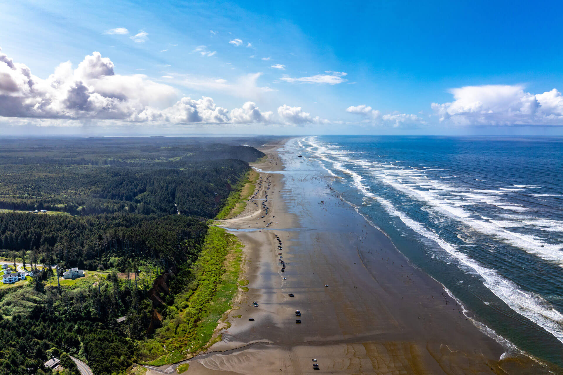 An aerial view of a long sandy beach and waves along the Pacific Coast